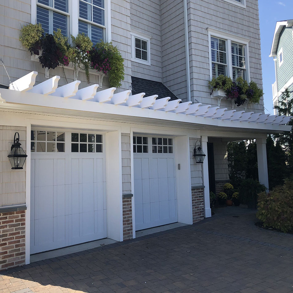 Showcasing a stylish home with PVC rafter tails, this image features a modern architectural design with vibrant flowers and a spacious driveway. Ideal for enhancing curb appeal.
